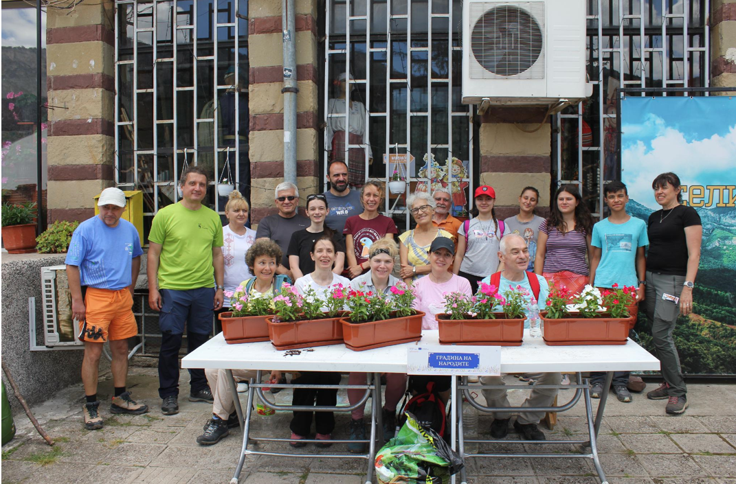 Visitors and Zgorigrad residents stand together behind newly planted flower boxes outside the community centre.