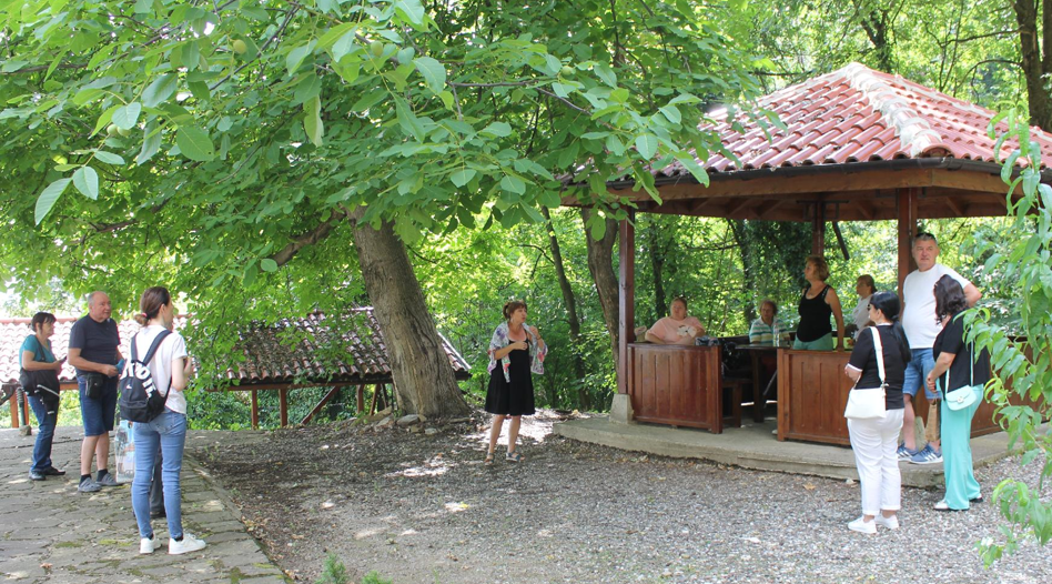 Visitors and local hosts gather beside a wooden pavilion in a green area during the Bistrets Path of Tradition pilot.