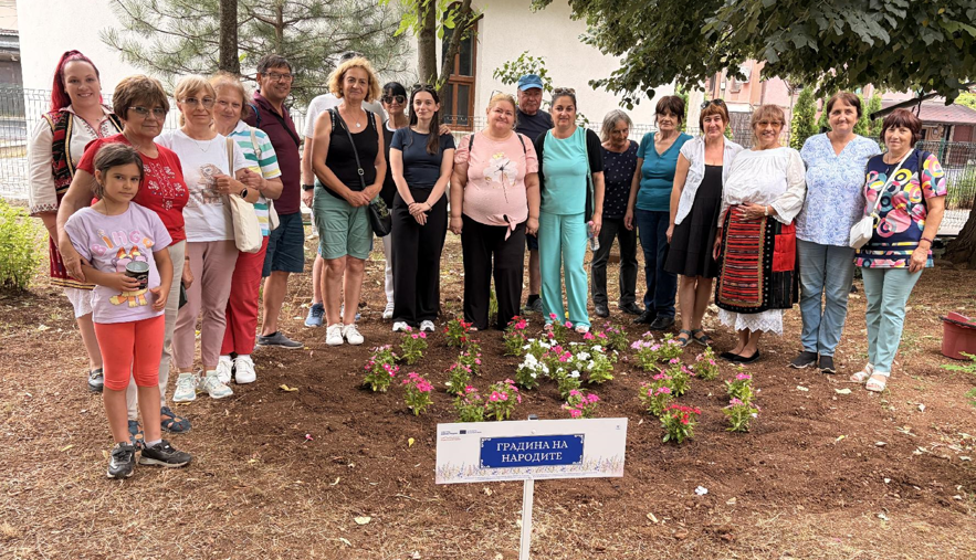 Local residents and visitors stand together beside newly planted flowers in the Garden of the World in Bistrets.
